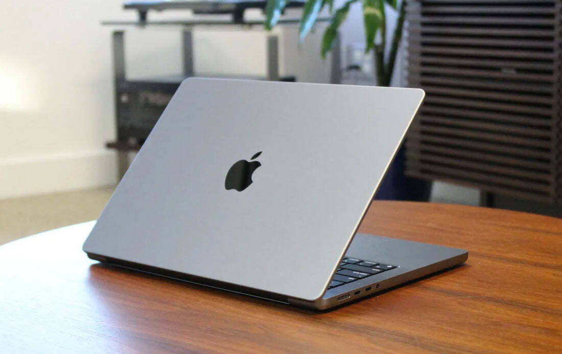 Silver laptop with Apple logo on a wooden table.