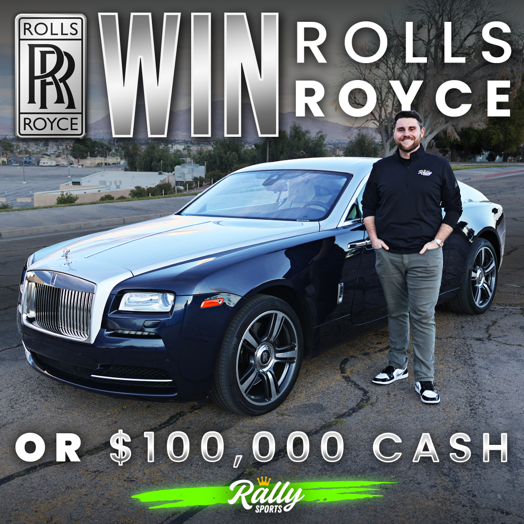A man stands next to a blue and silver Rolls Royce for a giveaway.
