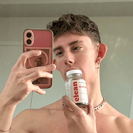 Person taking a mirror selfie holding a bottle labeled 'Clean.'