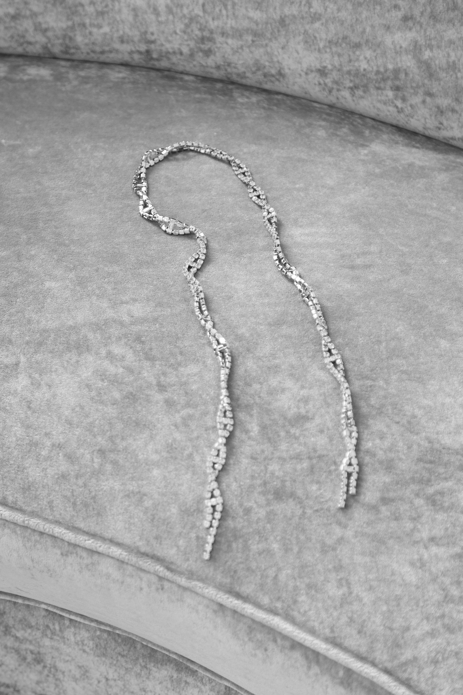 A twisted, beaded necklace lying on a textured surface.