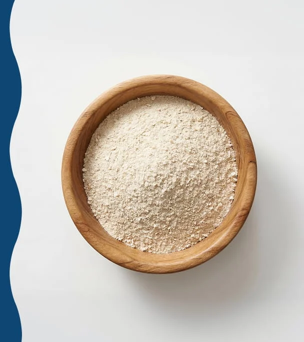 An overhead shot of a wooden bowl filled with a finely ground powder on a white and blue background.
