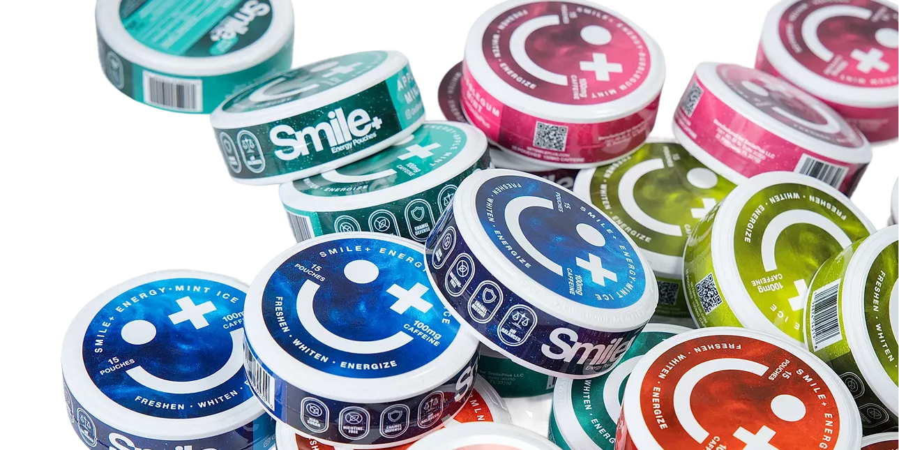 A pile of colorful, round containers of Smile+ Energy Pouches scattered against a green background.