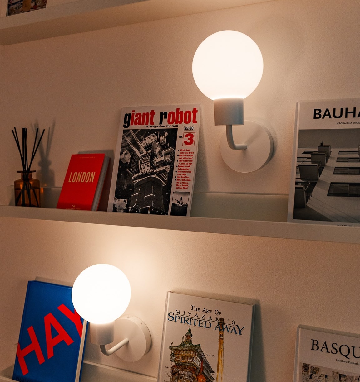 Books and two wall-mounted glowing lights on white shelves.