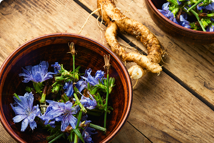 Bowl of blue flowers and roots on a wooden surface.