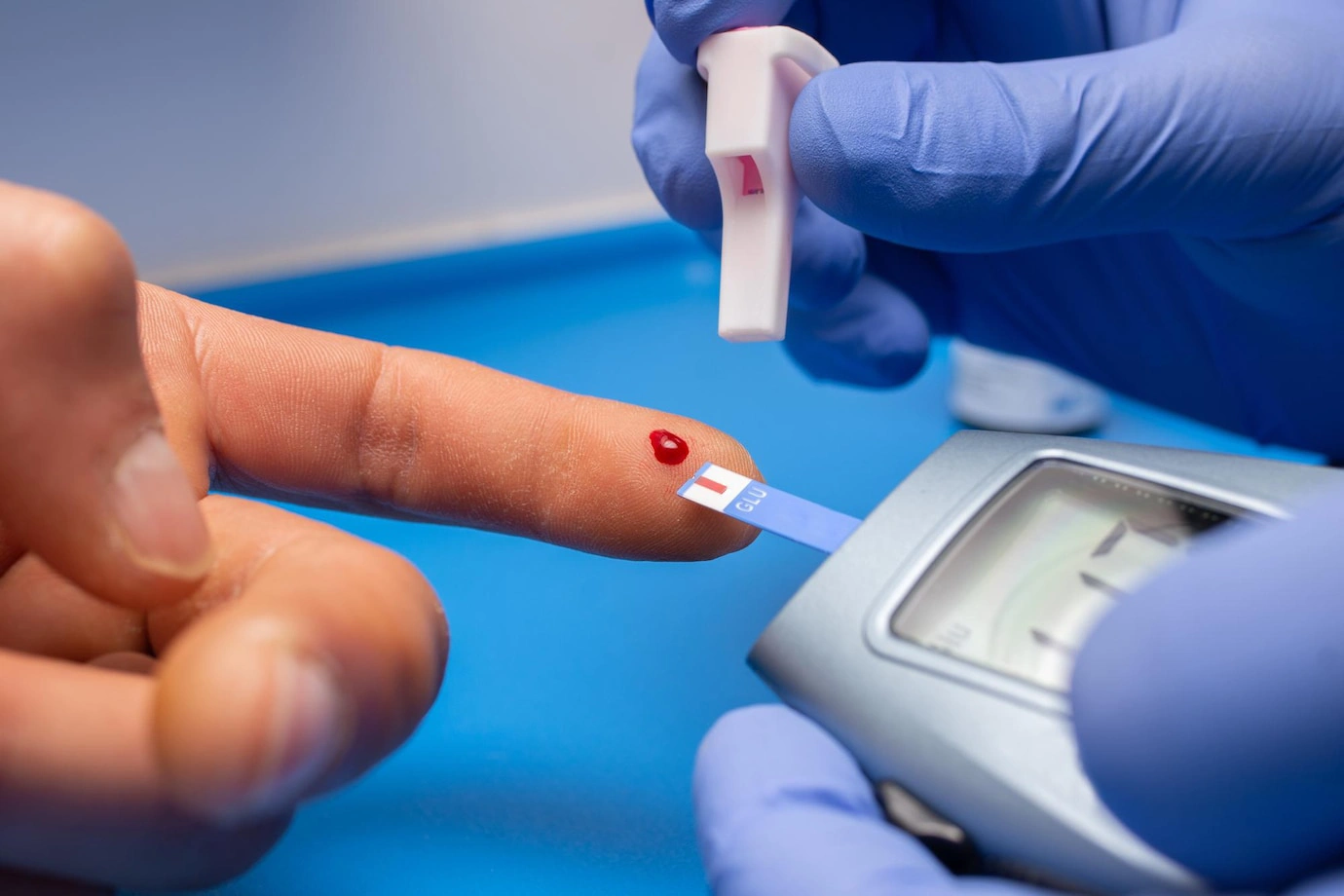 Person testing blood sugar with a glucometer and test strip.