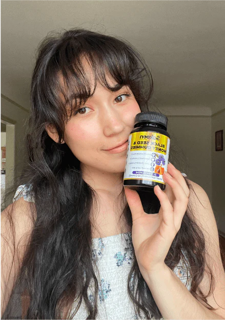 Person holding a bottle of black seed and honey gummies.