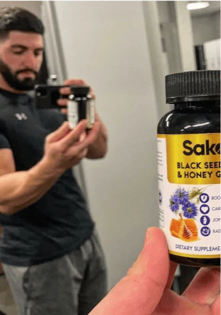 Person taking a mirror selfie holding a bottle of dietary supplement.