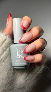 Hand holding nail polish with red-tipped nails.