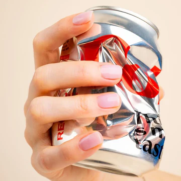 Hand holding a crushed aluminum can with red text.