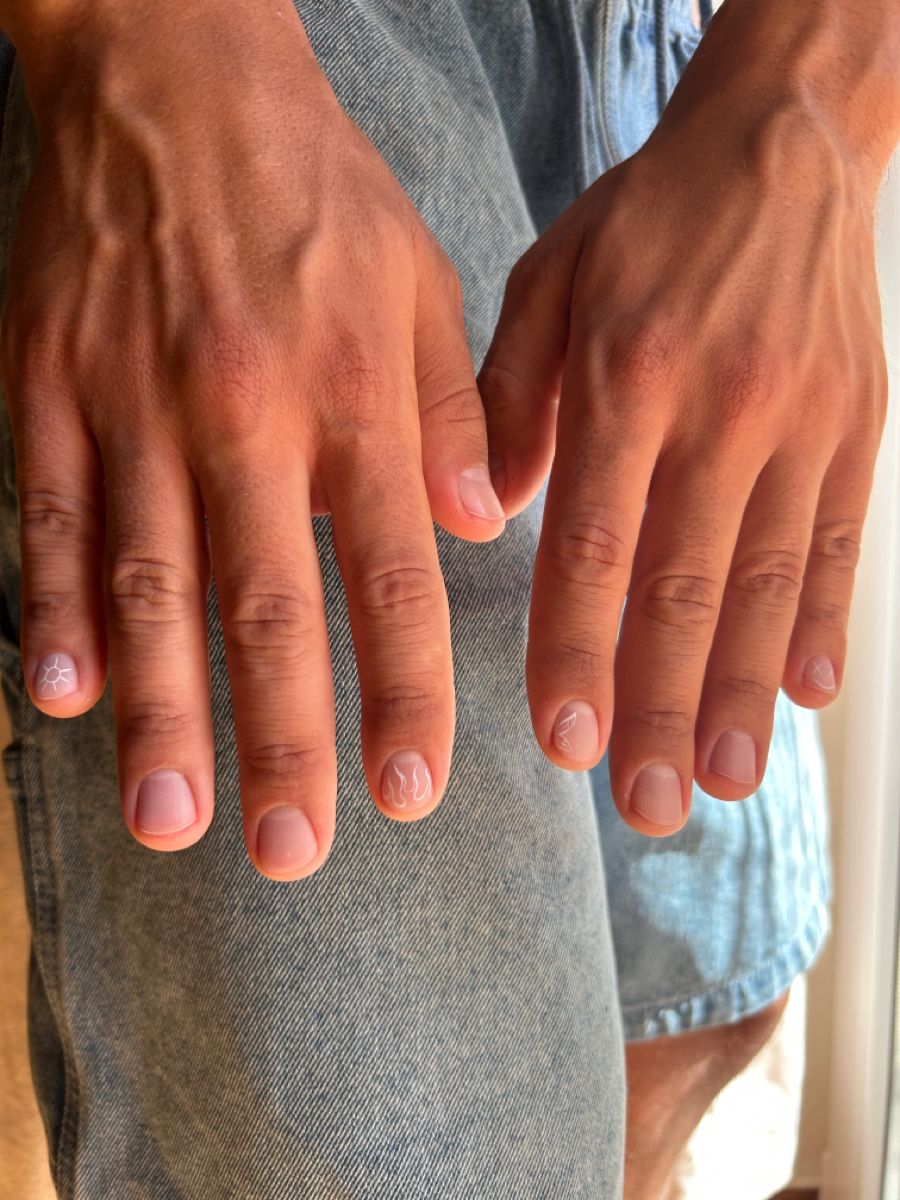 Close-up of hands with simple nail art, wearing denim shorts.