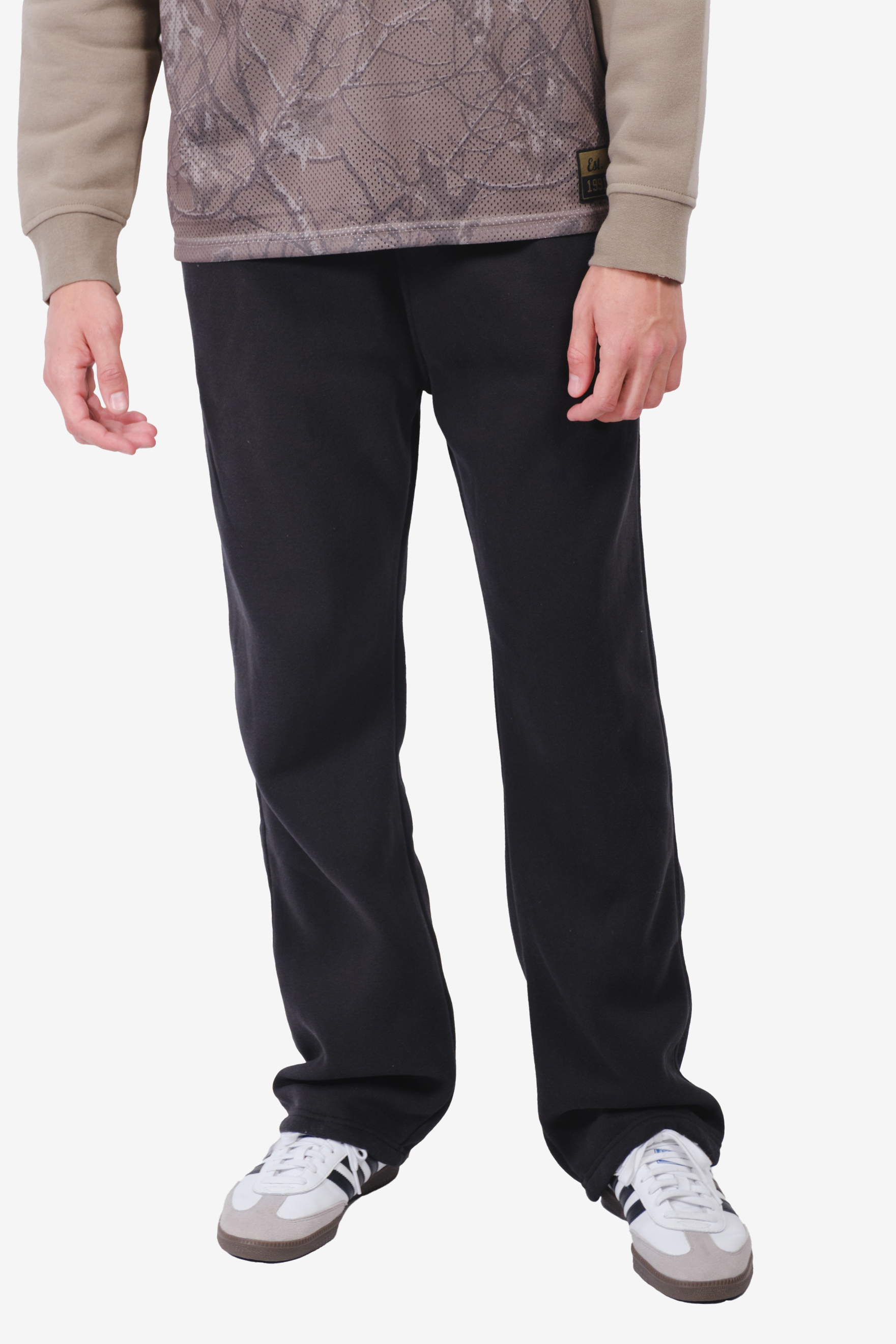 Person wearing black pants, patterned shirt, and white sneakers.