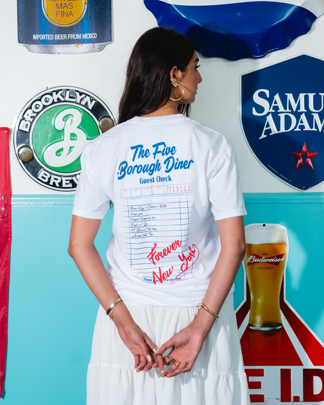 Person wearing a diner-themed shirt, standing near beer brand signs.