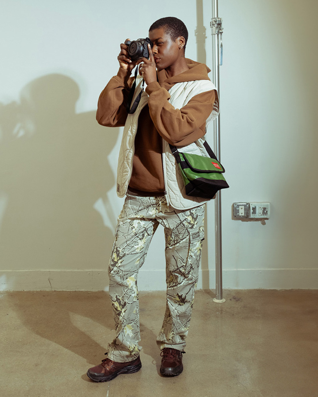 Person wearing black pants, patterned shirt, and white sneakers.
