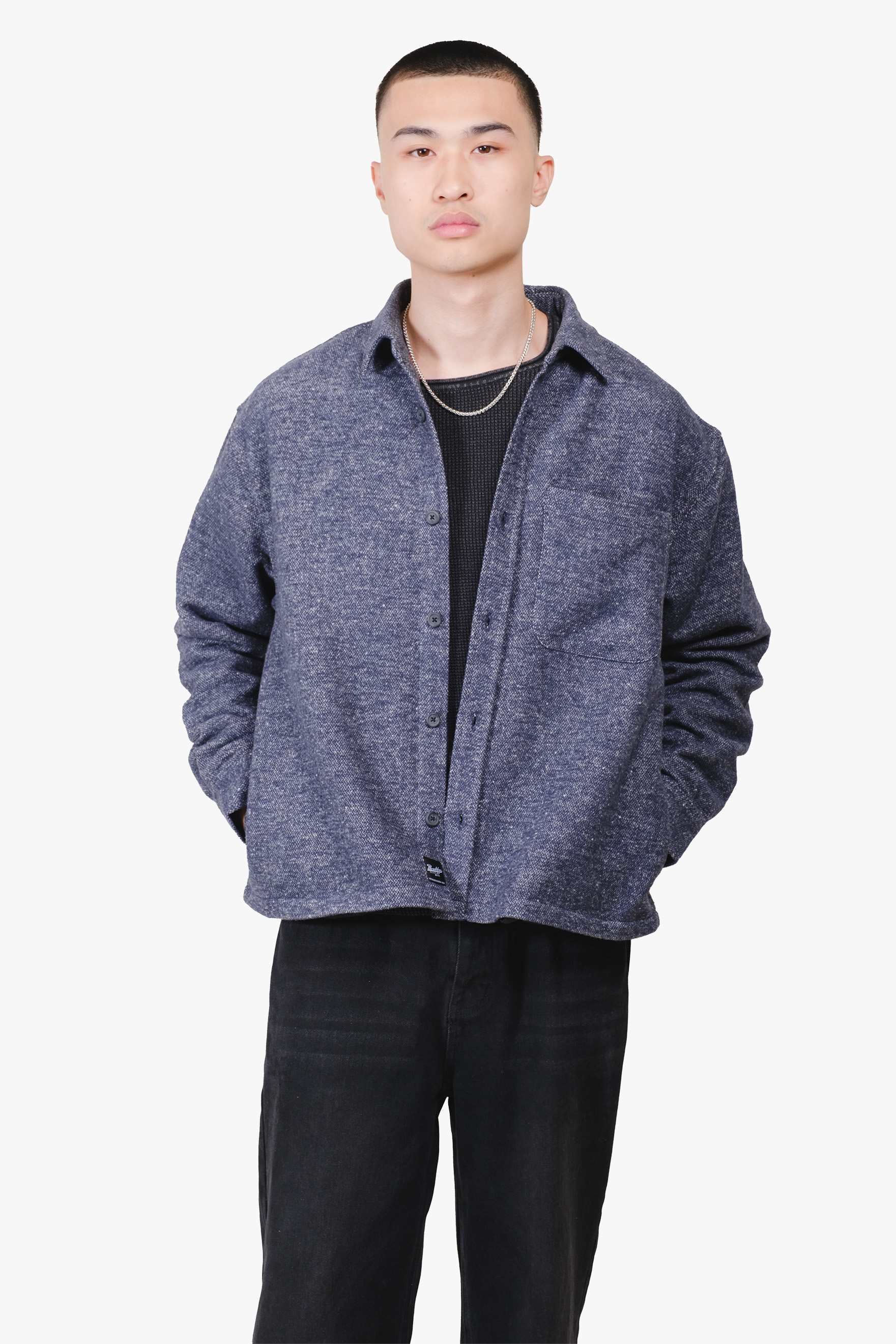 Person wearing a blue button-up jacket and black pants against a white background.