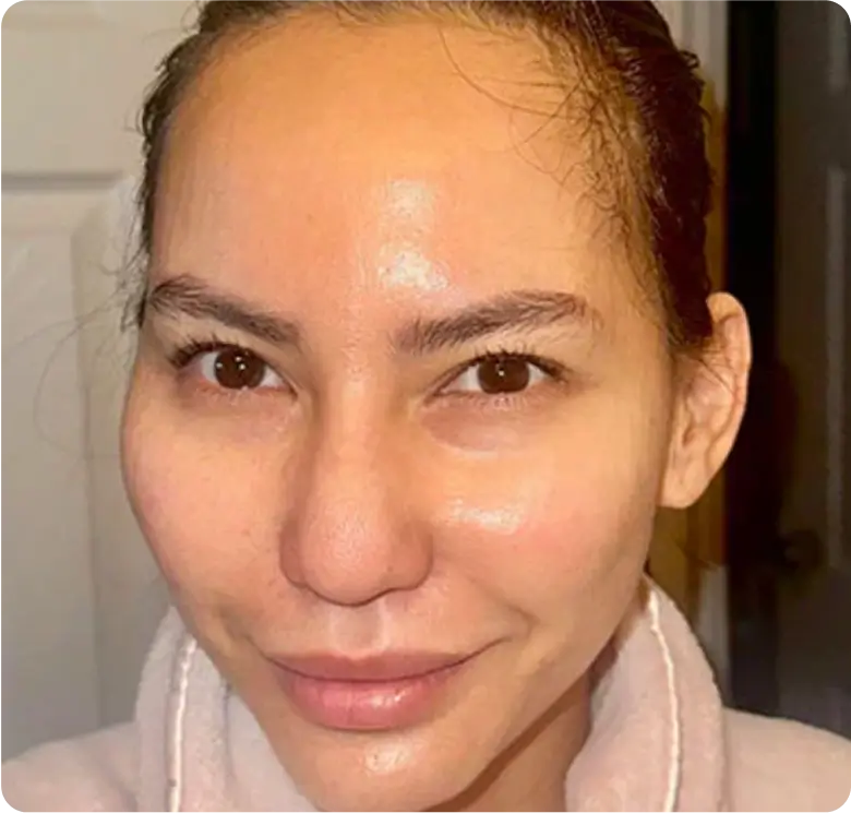 Person smiling in a bathrobe with a neutral background.