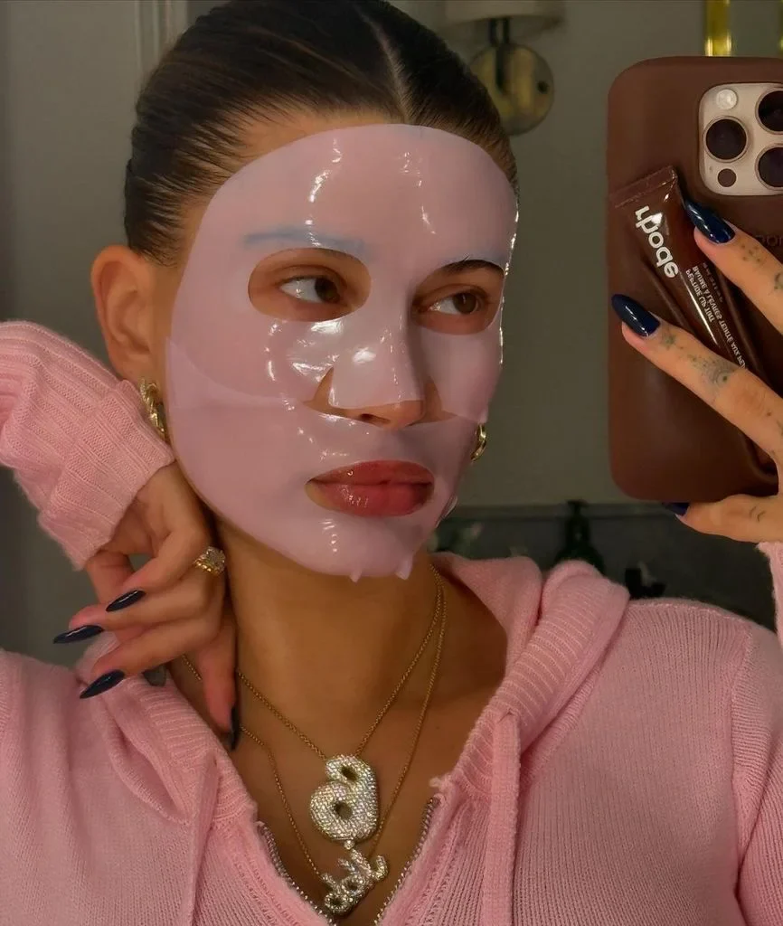 Person wearing a pink face mask, taking a selfie in a mirror.