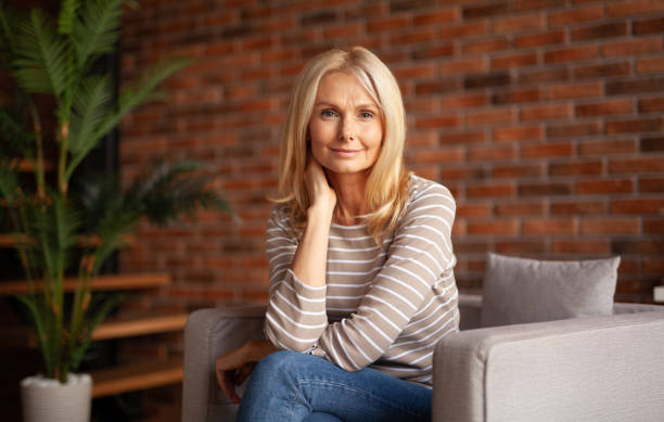 Woman sitting on a couch in a room with a brick wall background.