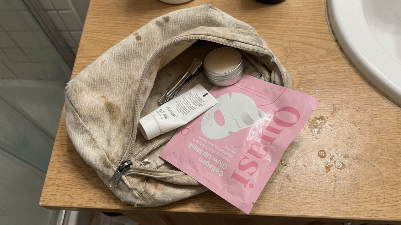 Open cosmetic bag with skincare products on a bathroom counter.