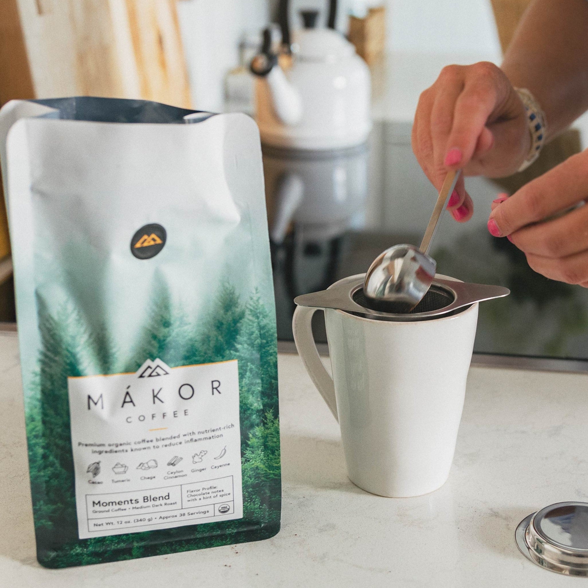 Bag of Makor coffee beside a person preparing a brew in a mug.
