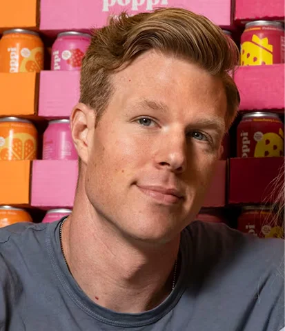 Person in front of stacked colorful beverage cans.