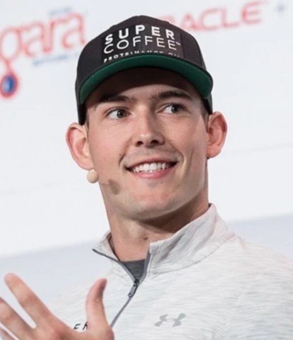 Person wearing a 'Super Coffee' cap, smiling and gesturing while speaking.