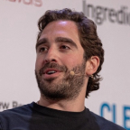 A man speaking on stage with a headset microphone.