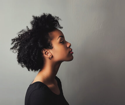 Profile of a woman with curly hair against a plain background.