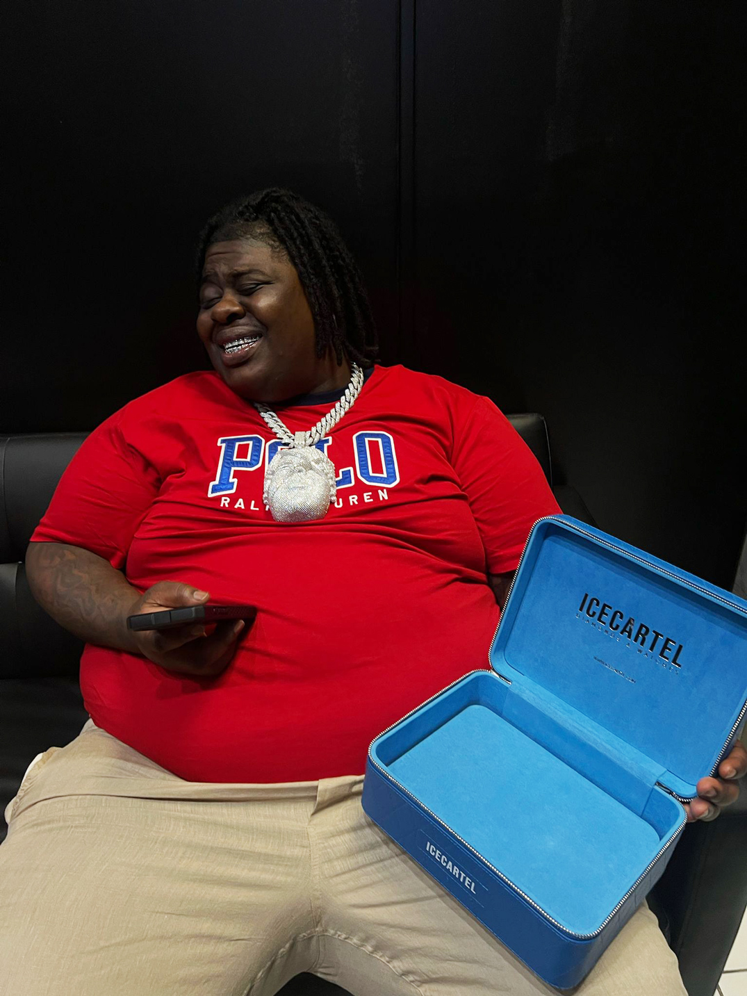Person in red shirt holding a phone and an open blue box.