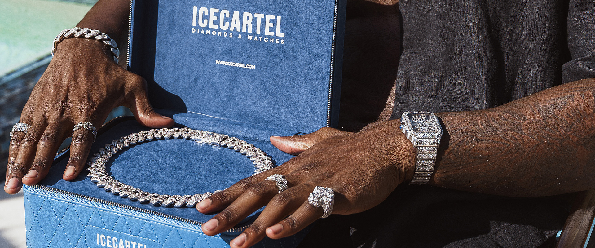 A person wearing diamond jewelry opens a blue ICECARTEL box holding a large diamond chain.