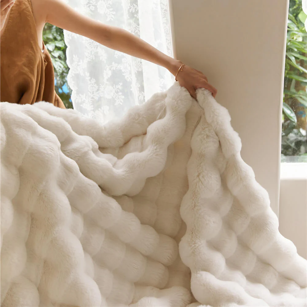 Person holding a textured white blanket near a window.