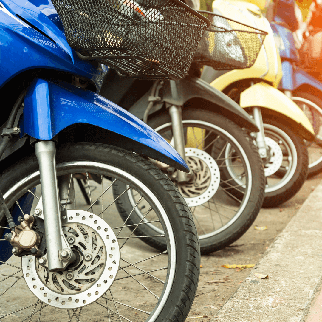 Row of parked motorcycles with front baskets.