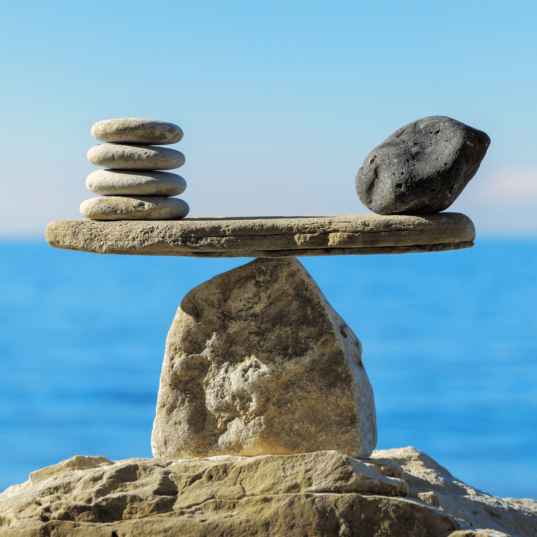 Balanced stones on a rock with a blue sea background.