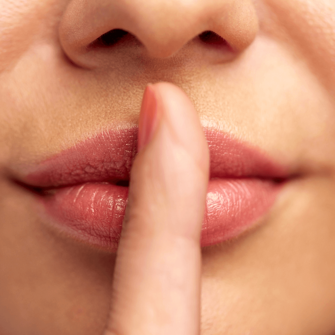 Close-up of a finger on lips, suggesting silence.