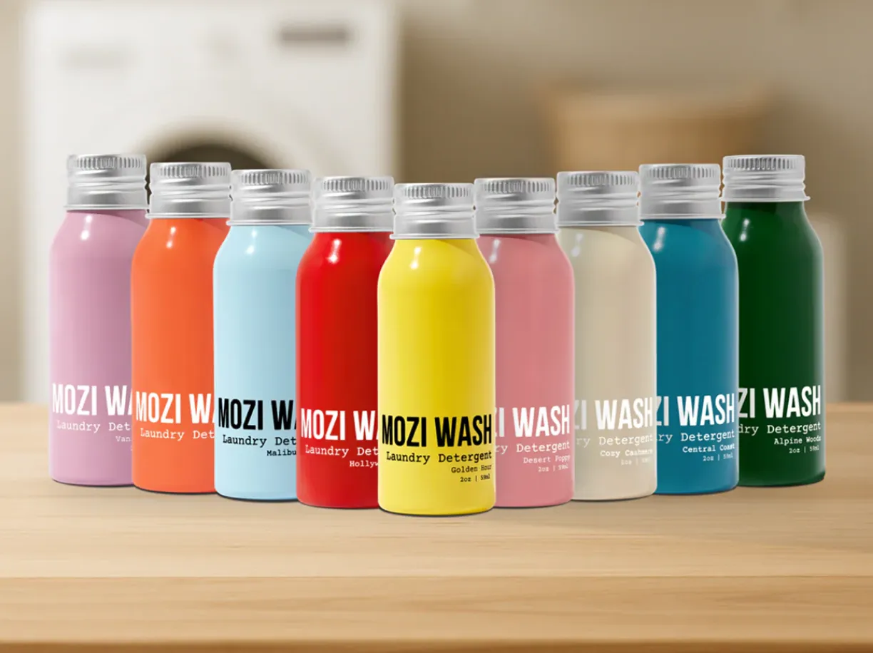 A row of colorful aluminum bottles of MOZI WASH laundry detergent on a wooden surface.