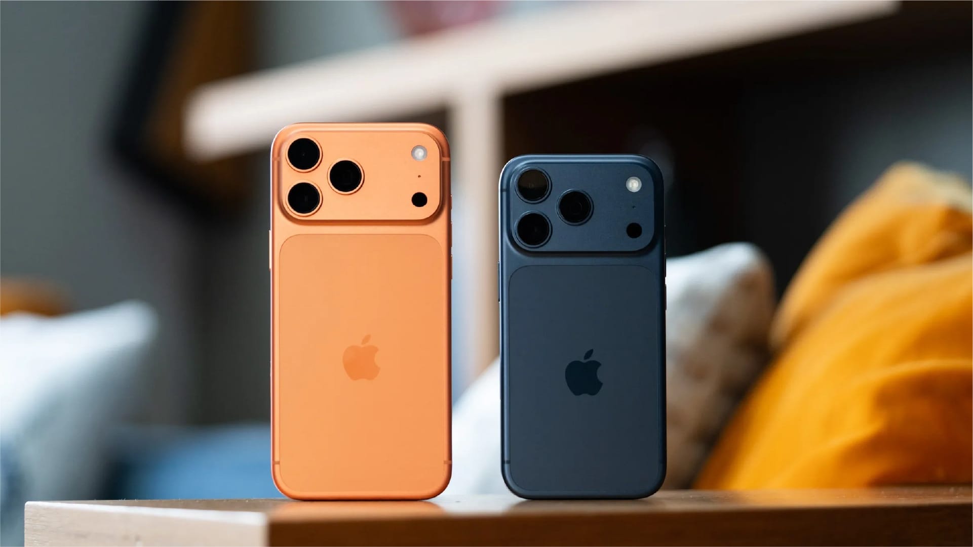 Two smartphones on a wooden surface, one orange and one black.