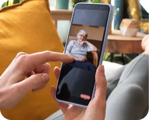 woman holding mobile phone using jubileetv app to drop in on ederly grandmother