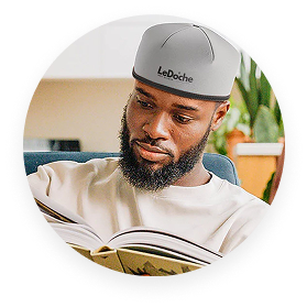Person reading a book while wearing a gray cap indoors.