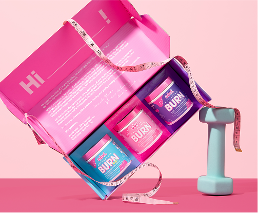 Open pink box with three supplement jars and a teal dumbbell on a pink background.