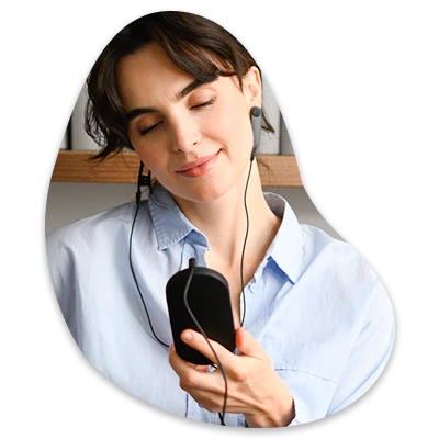 Person wearing earphones, holding a smartphone, and smiling with eyes closed.