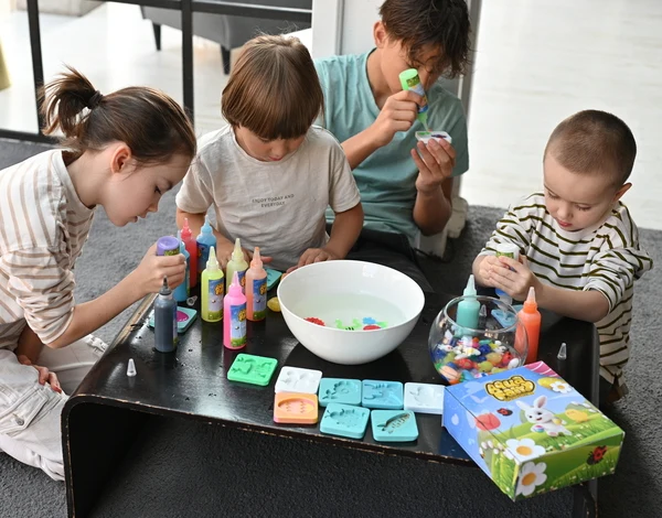 Children engaged in a crafting activity with colorful supplies on a table.
