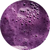 Close-up of purple liquid with bubbles inside a circular frame.