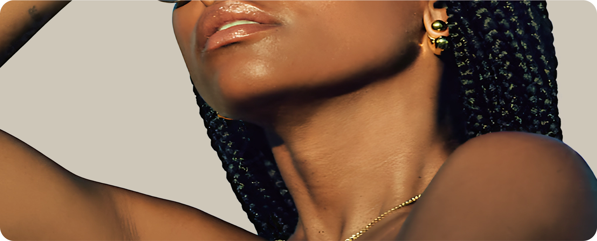 Close-up of a person's neck and chin, wearing earrings and braided hair.