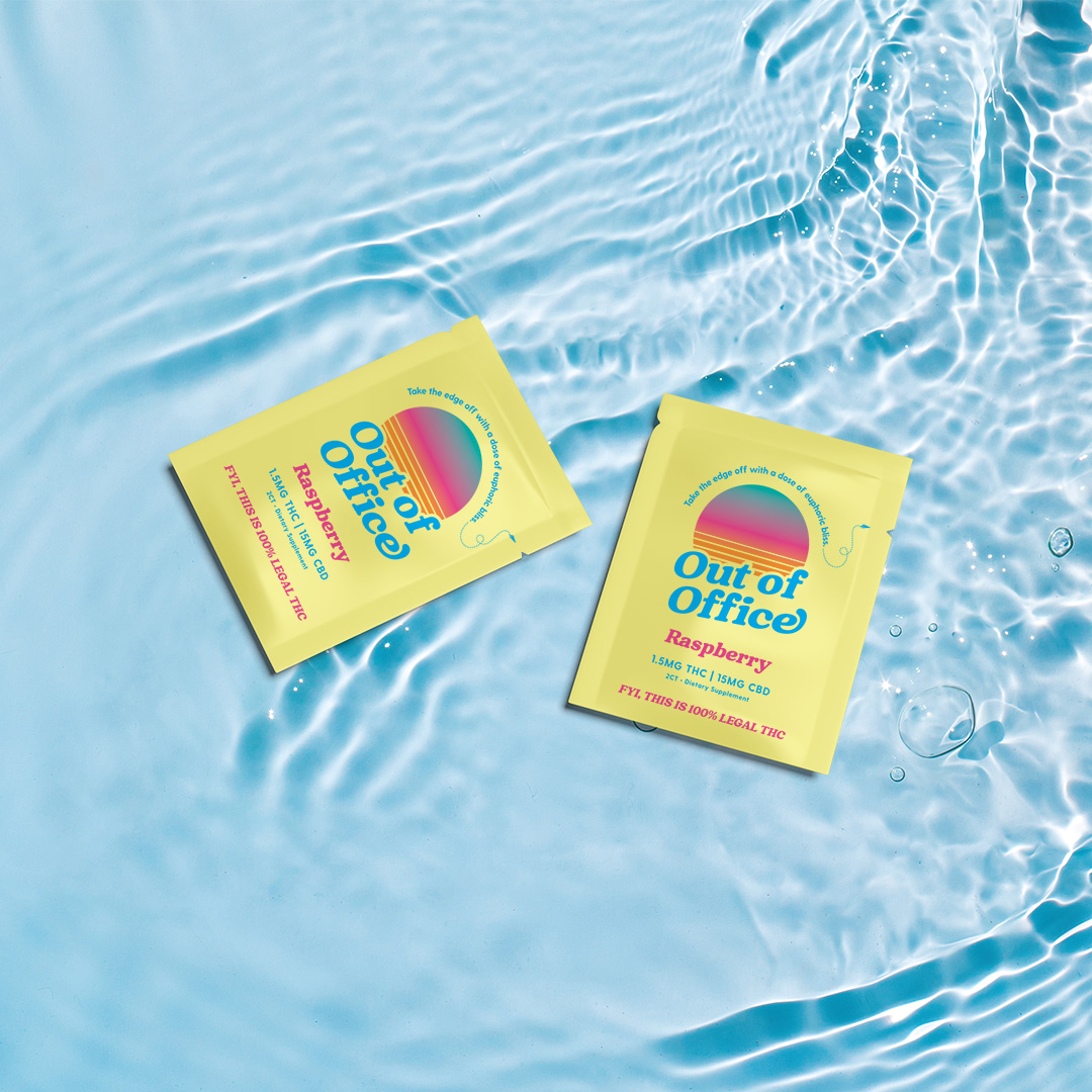 Two yellow packets of Out of Office Raspberry supplements floating on clear, rippling water.