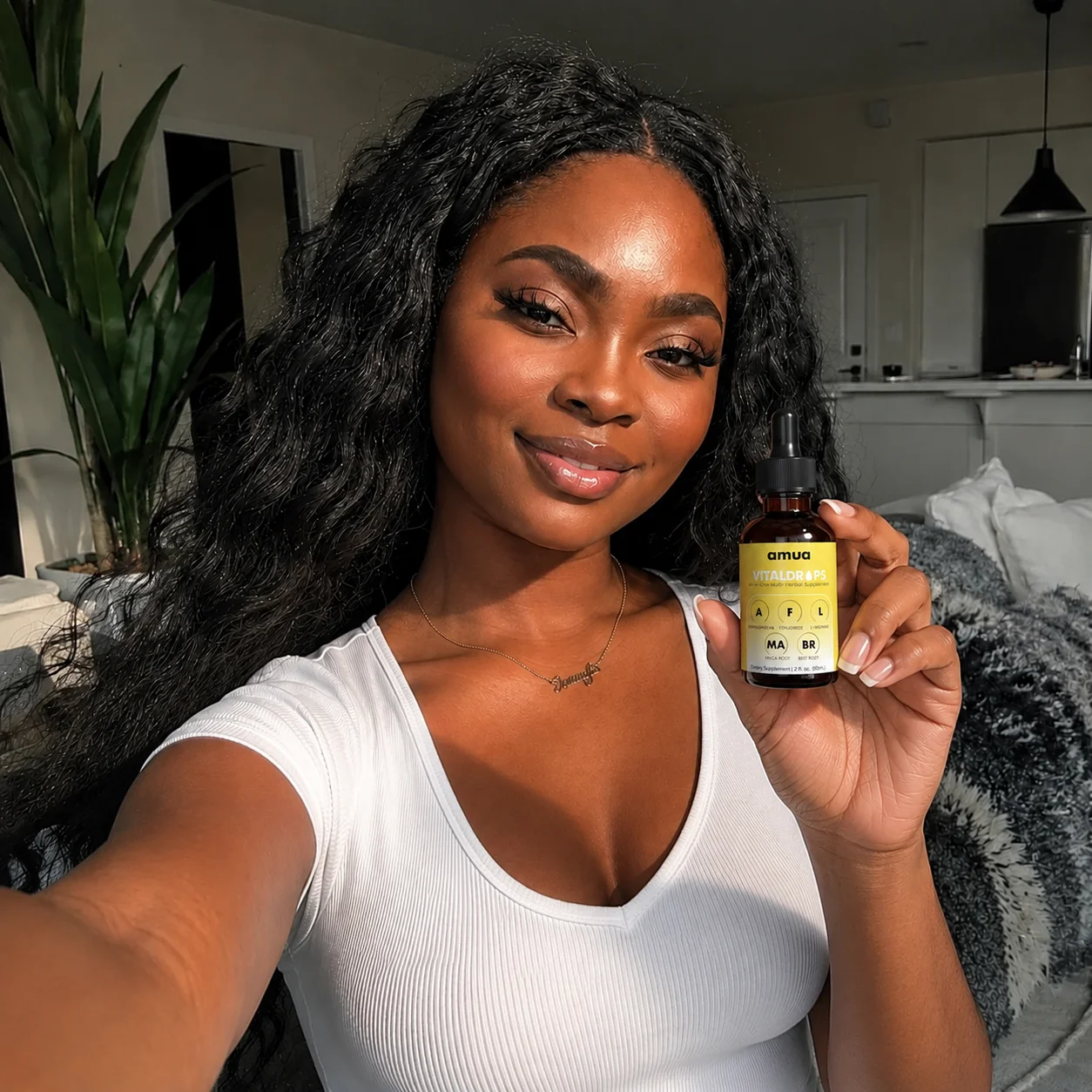 A woman with long dark hair smiles while taking a selfie and holding a small dropper bottle.