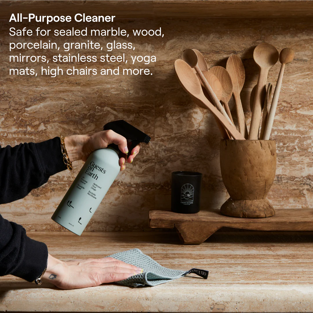 A person sprays a cleaner onto a marble countertop while wiping it with a cloth.