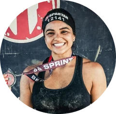 Person smiling with a medal around their neck, wearing a headband and tank top.