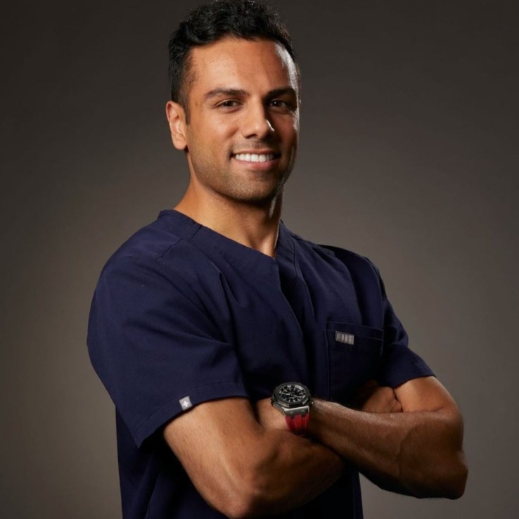 Person in navy scrubs smiling and crossing arms.