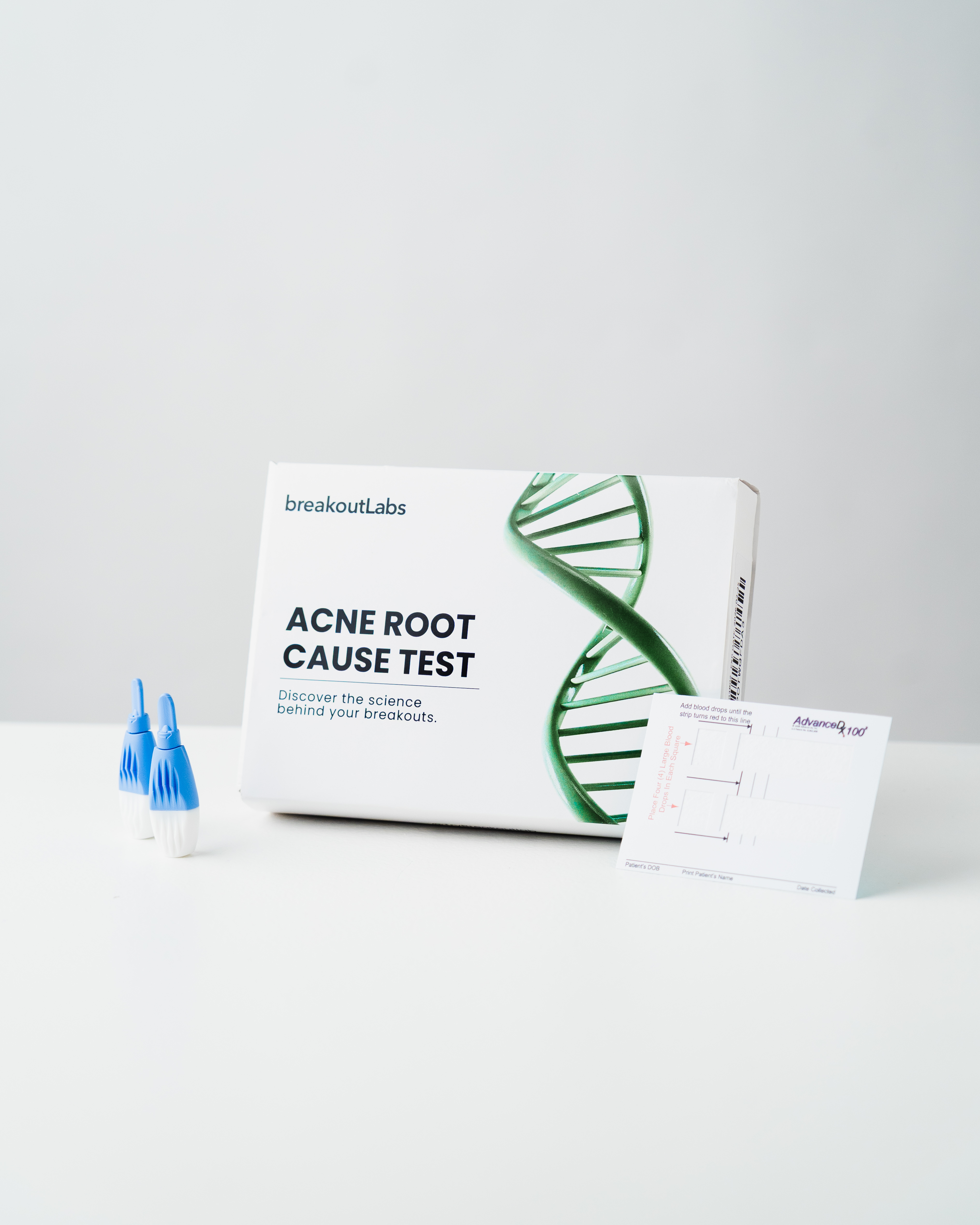The breakoutLabs Acne Root Cause Test kit with box, two lancets, and a blood spot collection card.