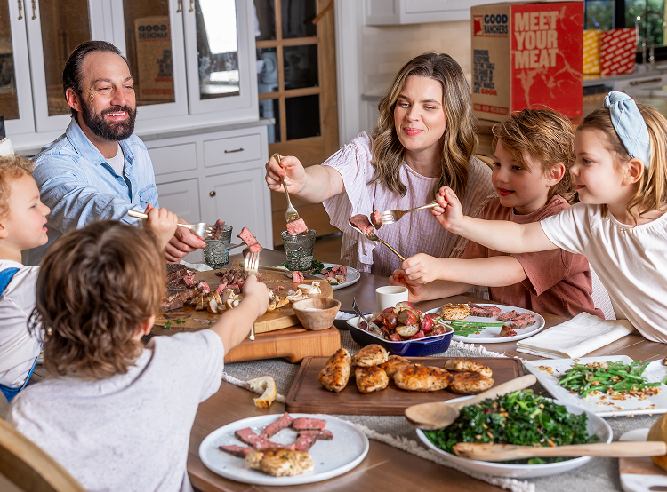 Family sharing a meal with various dishes on a dining table.