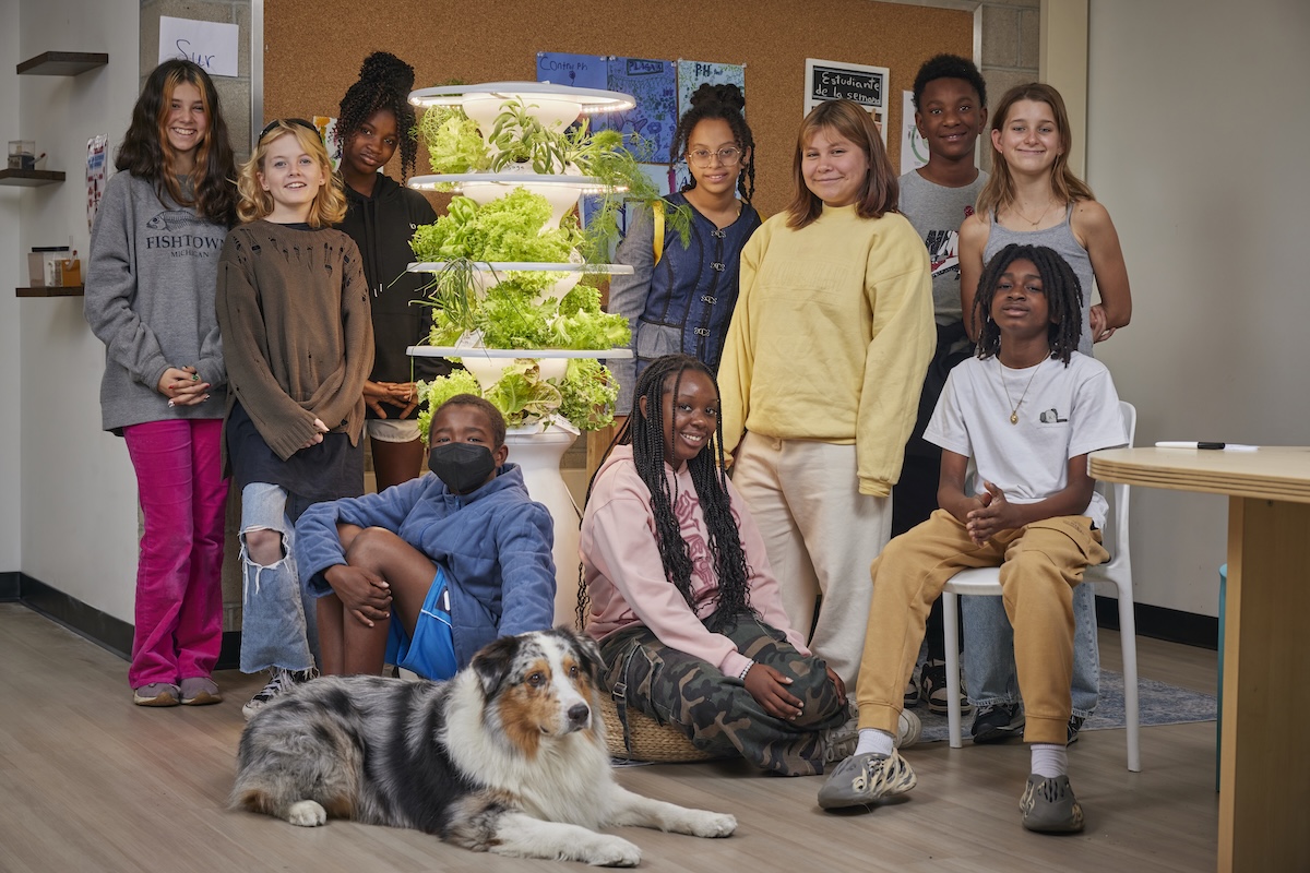 Group of children and a dog in a room with vertical garden.